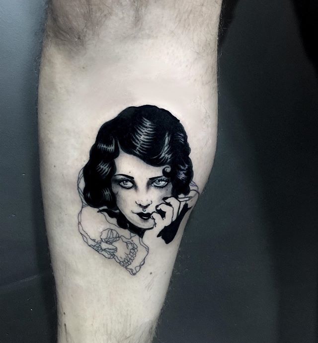 Black tattoo of a ladies head and skull on the calf