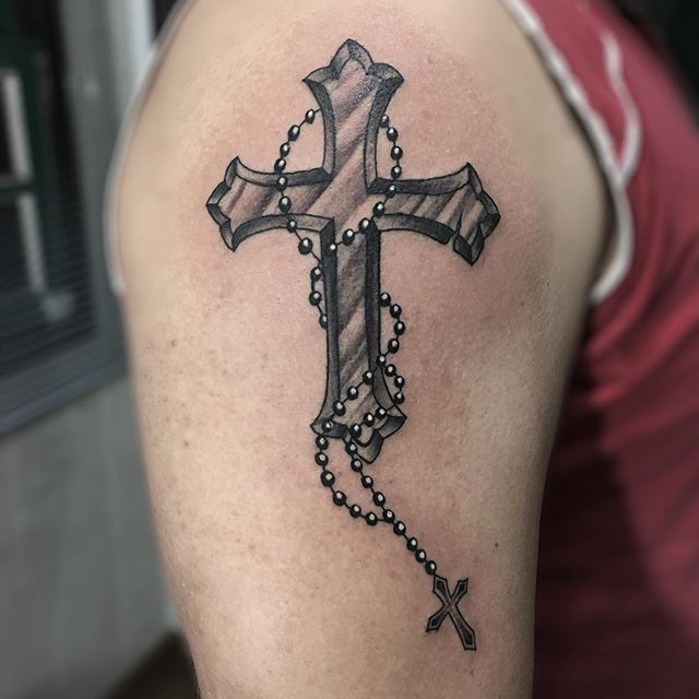 Black tattoo of a cross with a rosary on the right shoulder