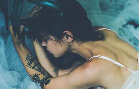 girl laying on bed with tattoo on the hand
