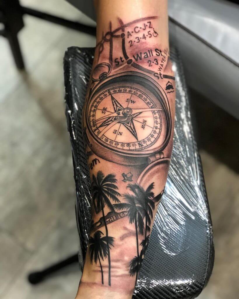 Black and Gray Compass tattoo with palm trees on the forearm