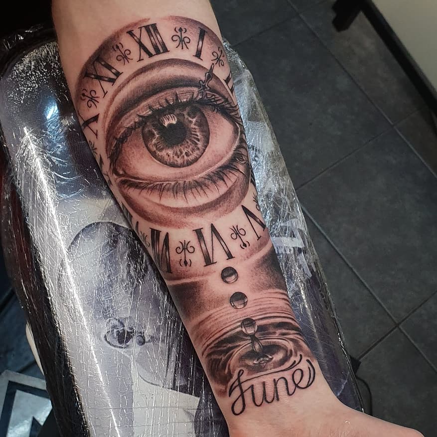 Black Male tattoo of a watch with an eye in it, on the left forearm