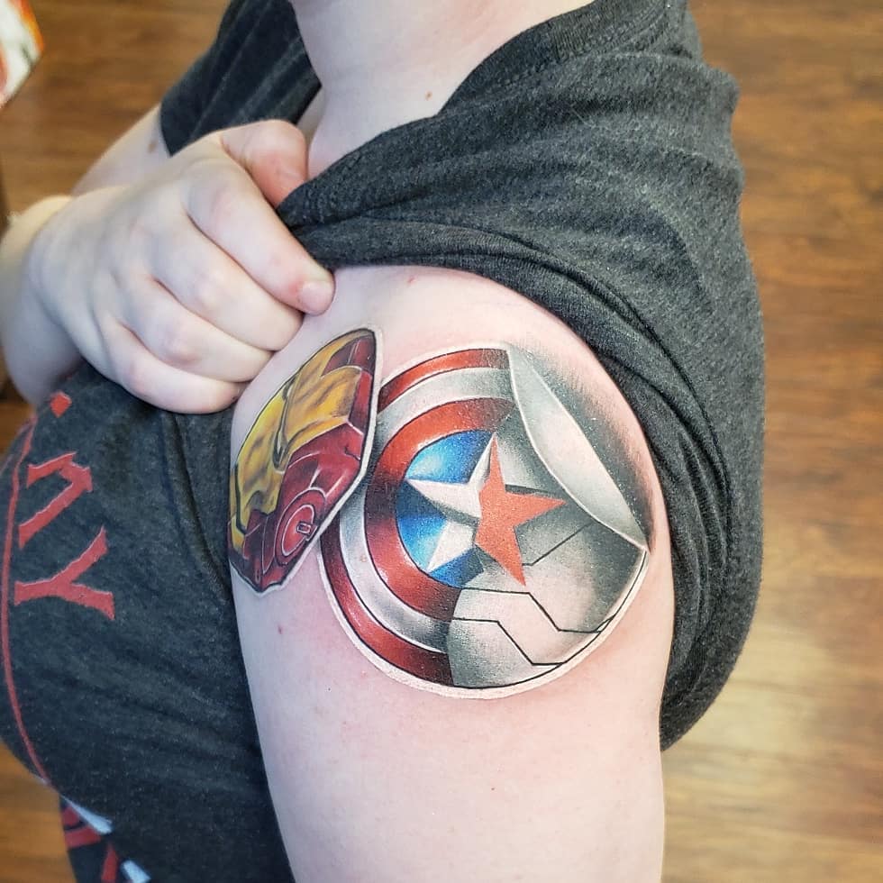 Sticker tattoo of Captain Americas shield and of Iron mans helmet on the shoulder