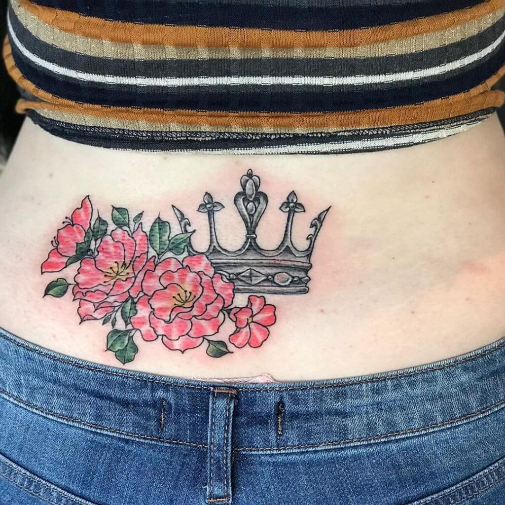 Color Female tattoo of a crown and flowers above the butt