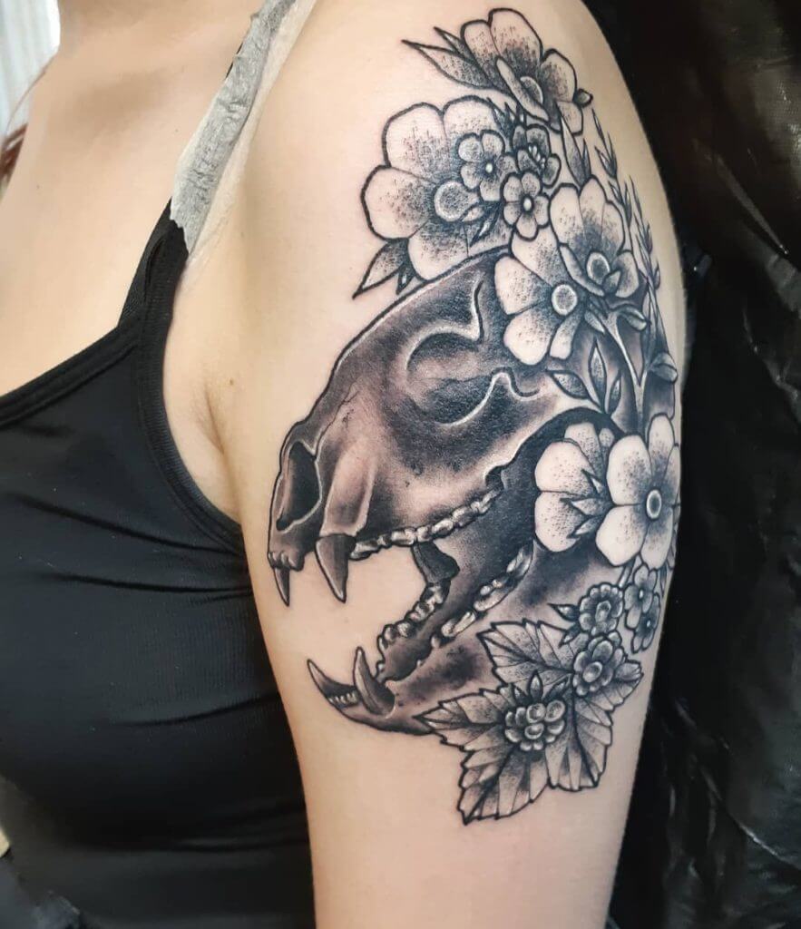 Women black and gray dotwork tattoo of a skull of the beast with flowers on the left shoulder