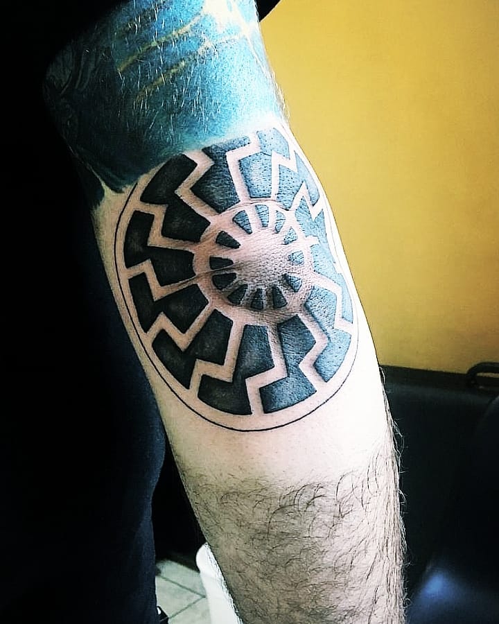 Black sun tattoo on the arm