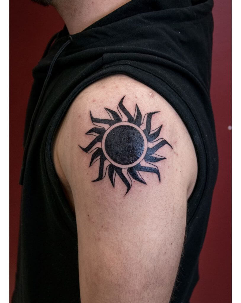 Tribal black sun tattoo on the left shoulder