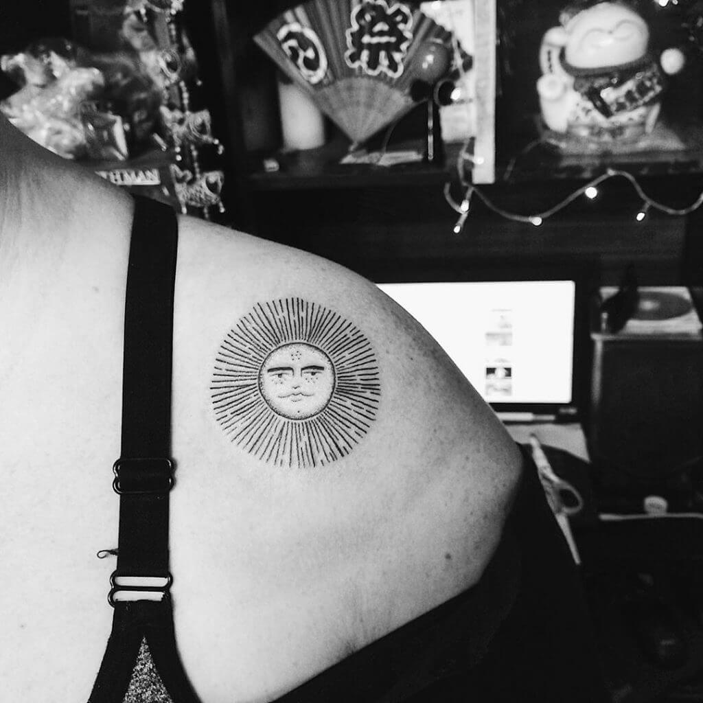 Black sun tattoo on the shoulder