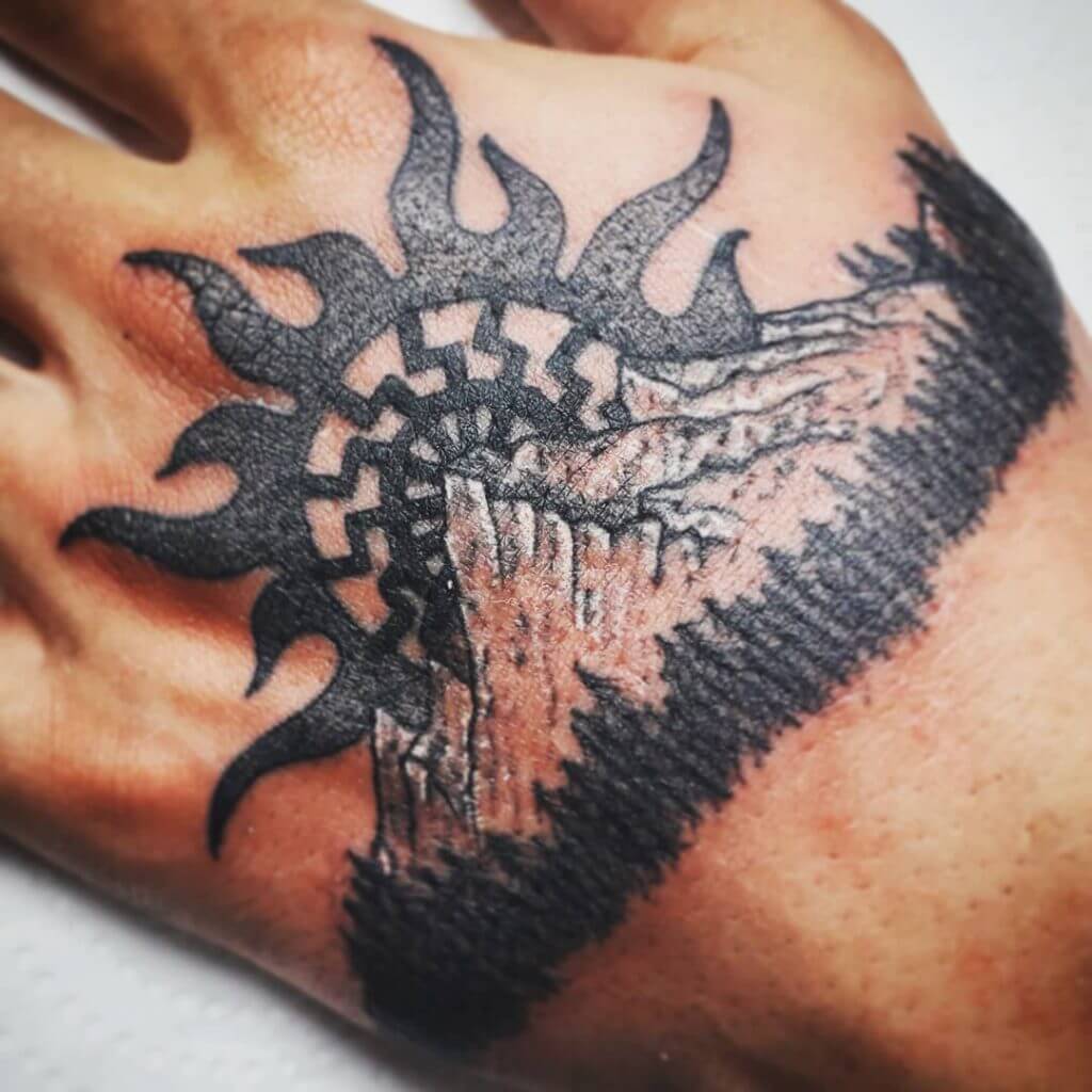 Black sun tattoo on the hand