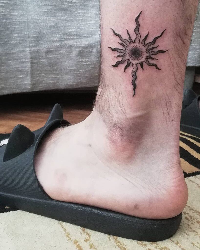 Black sun tattoo on the ankle
