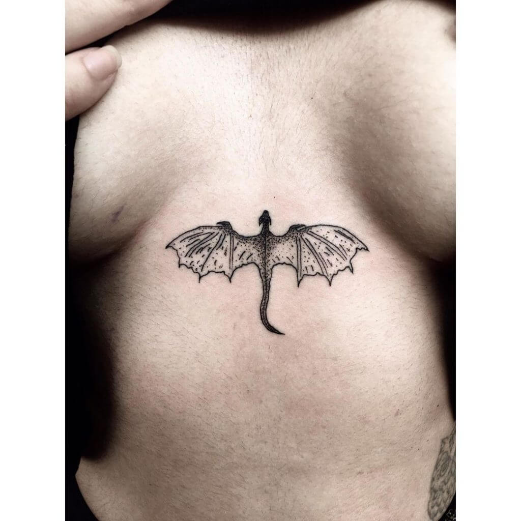 Black dragon tattoo for woman between the breasts