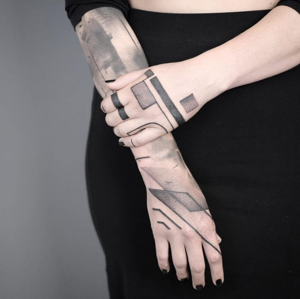 Abstract geometric tattoo on right forearm and left hand