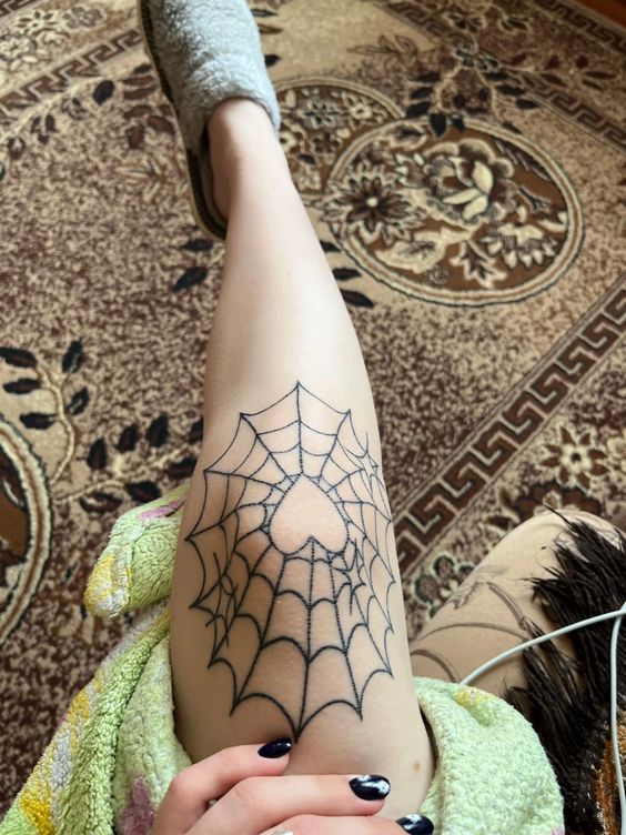 Spiderweb tattoo on the left knee