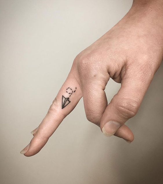 The charm of a paper airplane finger tattoo