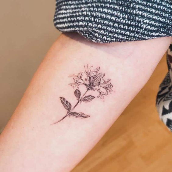 Delicate honeysuckle arm tattoo artwork emphasizing the timeless symbolism.