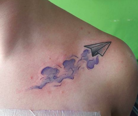 Delicate paper airplane shoulder tattoo design representing the themes of freedom, innocence, and boundless creativity.